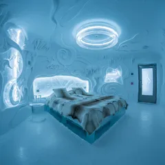 Ledový hotelový pokoj s modrým osvětlením a ledovou postelí v moderním stylu.